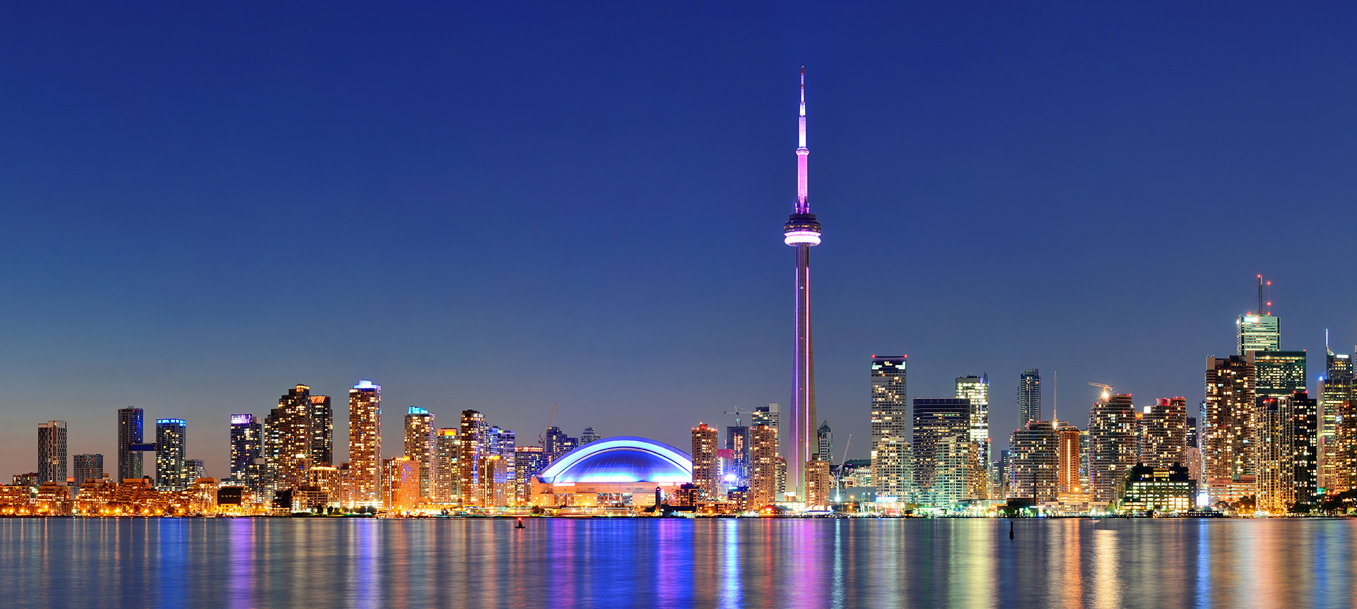 Toronto cityscape panorama at dusk over lake with colorful light.
